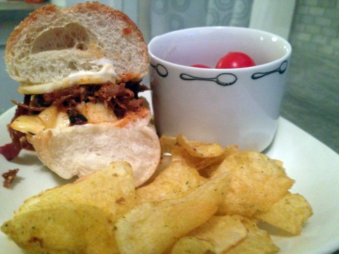 Image of leftover pulled pork turned into sandwich; with chips and baby tomatoes