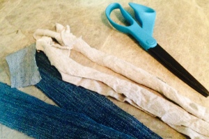 Image of scissors next to strips of denim and t-shirt material